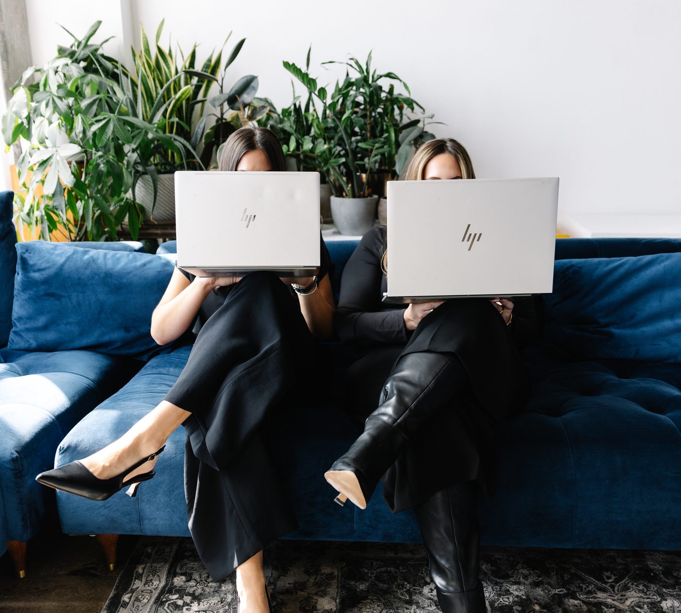 Two training participants on a sofa preparing their presentations on laptops